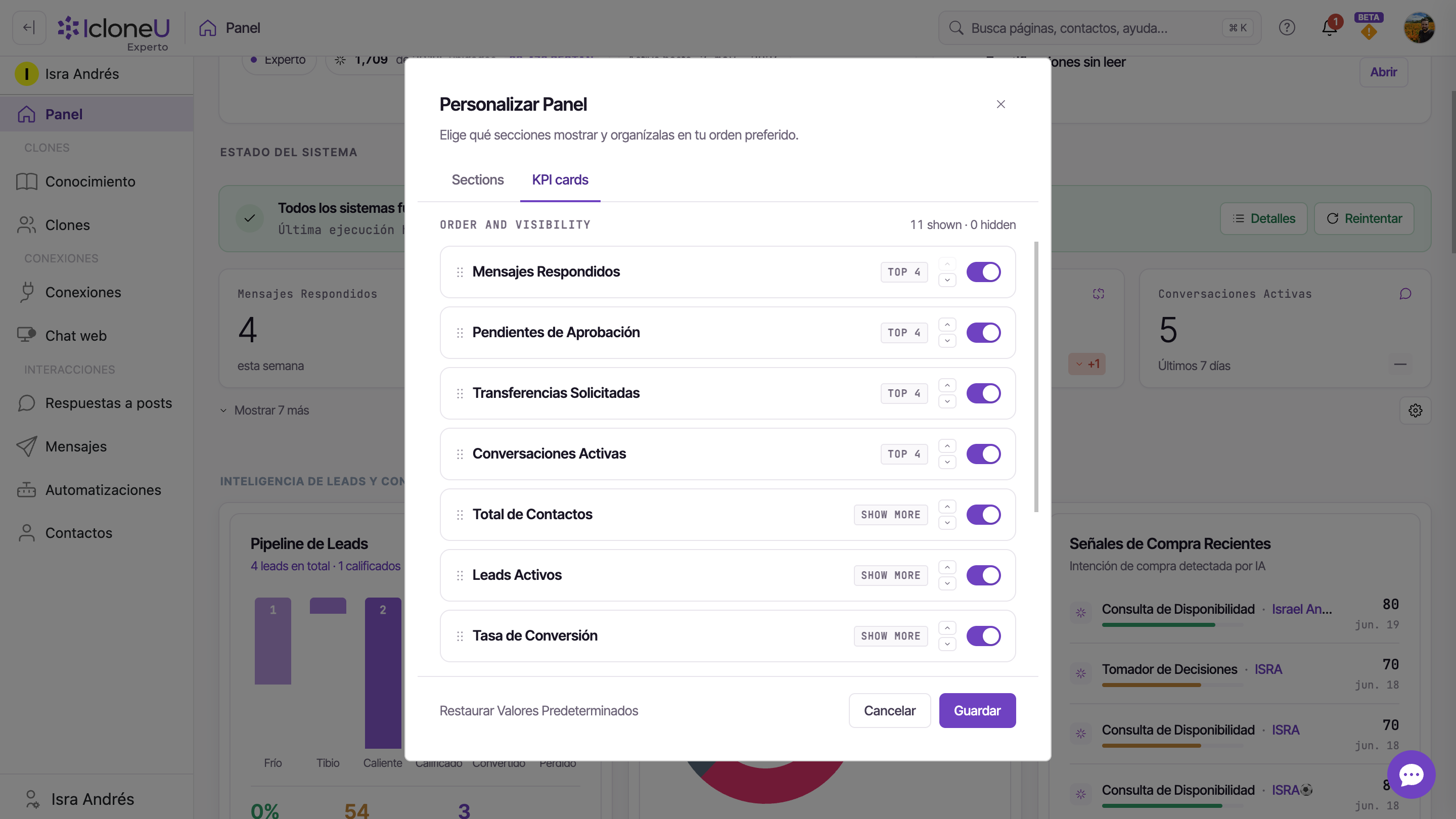 El diálogo Personalizar Panel en la pestaña KPI cards: filas con asas para arrastrar, insignias TOP 4 / SHOW MORE / HIDDEN e interruptores de encendido, el conteo shown / hidden y los controles Restaurar Valores Predeterminados / Cancelar / Guardar